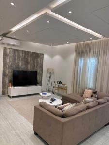 a living room with a large couch and a flat screen tv at Smart luxury apartment 3bedrooms in Riyadh