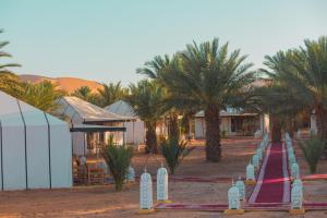 een rij palmbomen voor een gebouw bij Morocco Luxury Desert Camp in Merzouga