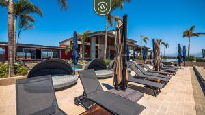 een rij chaise loungestoelen en parasols bij 2BR Penthouse in Nuevo Vallarta - Terrace - Pool in Nuevo Vallarta 