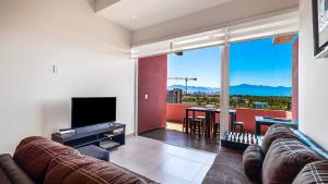 een woonkamer met een bank en een flatscreen-tv bij Equipped 3BR House - Pool - Gym - 5 min to Beach in Nuevo Vallarta 