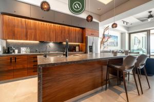 een keuken met houten kasten en een aanrecht met krukken bij Luxury 2 BR Condo with Beachview - Rooftop Pool in Puerto Vallarta