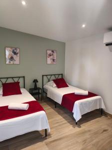 a bedroom with two beds with red and white sheets at Gîtes Néphélie votre cocon tout confort aux portes du Puy duFou - Climatisé, Terrasse, Parking in Les Épesses