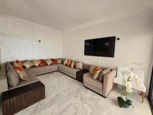 a living room with a couch and a flat screen tv at Zaouch house in Moulay Bousselham +2 photos