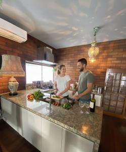 Un hombre y una mujer de pie en una cocina preparando comida. en 源泉かけ流し温泉&プライベートサウナ付き一棟貸しVilla Gensen One, en Yuzawa