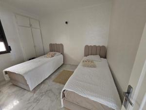two beds in a small room with white walls at Zaouch house in Moulay Bousselham