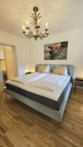 a bedroom with a large bed with a chandelier at Almrose Zauber by Alpenchalet Almrose in Oberau
