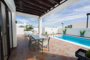 un patio con tavolo e sedie accanto alla piscina di Villa Nayra a Playa Blanca