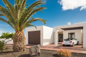 una palma di fronte a una casa bianca di Villa Nayra a Playa Blanca