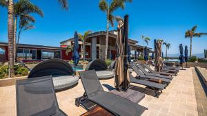 een rij chaise loungestoelen en parasols bij Equipped 3BR House - Pool - Gym - 5 min to Beach in Nuevo Vallarta 