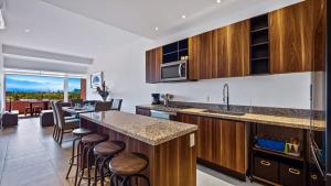 een keuken met houten kasten en een bar met krukken bij Equipped 3BR House - Pool - Gym - 5 min to Beach in Nuevo Vallarta 