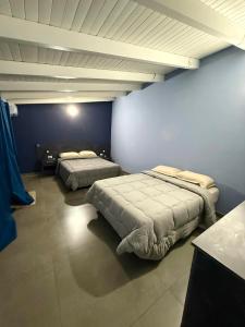 two beds in a room with blue walls at Hotel SMA in Puerto Iguazú