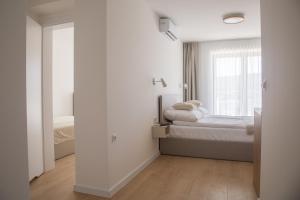 a white bedroom with a bed and a window at Nad Jeziorem in Rożnów