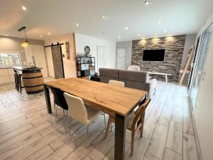 a dining room and living room with a wooden table and chairs at Villa nature in Léon