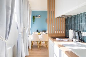 a kitchen with white cabinets and a blue wall at Le Green Escape in Sélestat