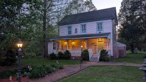 Una casa blanca con un porche con luces. en Garden and Sea Inn, en New Church