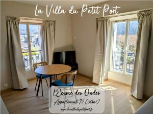 un soggiorno con tavolo, sedie e finestre di LA VILLA DU PETIT PORT - Appartements & chambres ad Aix-les-Bains