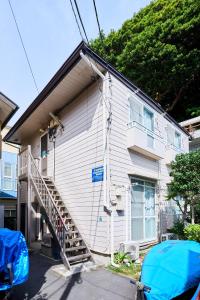 a white house with a staircase in front of it at Enoshima Apartment Hotel in Fujisawa