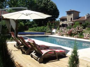 un grupo de sillas y una sombrilla junto a la piscina en La Grange Terrou en Saint-Germain-de-Confolens