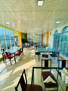 Un comedor con mesas y sillas y ventanas. en Grand Selim Resort & Tour – GSRT, en Sreemangal