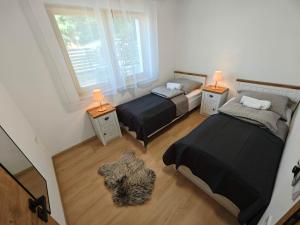 two beds in a room with two lamps on tables at Dióliget Apartman in Orfű