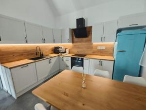 a kitchen with white cabinets and a wooden table at Dióliget Apartman - free e-bikes in Orfű