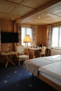 a hotel room with a bed and a table and chairs at Hotel Sonnenberg in Grindelwald