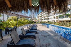 a row of chairs sitting next to a swimming pool at 2BR Condo with Private Terrace - Near to the Beach in Nuevo Vallarta 