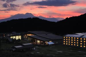 a building at sunset with mountains in the background at Hotel Tangram in Shinano