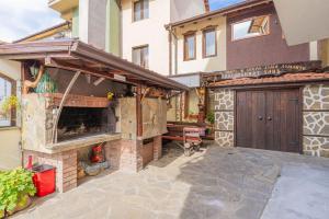a patio with a stone fireplace in front of a house at Къща за гости Костовският хан in Chepelare