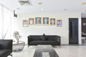 a living room with a black couch and pictures on the wall at Sunday Near Jonker Street in Kampong Morten