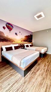 a bedroom with two beds and a painting of a hot air balloon at Hotel Panamby Guarulhos in Guarulhos