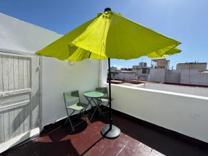 un parasol jaune sur un balcon avec une table et une chaise dans l'établissement Dar Lala Haniya, à Rabat