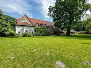 ein großes Haus mit einem großen Hof mit einem Baum in der Unterkunft Lüttje Paradies in Ruhwarden