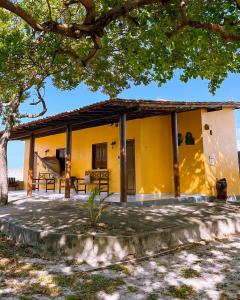 a yellow house with a tree in front of it at Pousada do Rancho in Barreirinhas