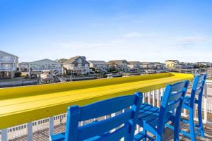 a row of blue chairs on a balcony with condos at Pug Life - Walk to the Ocean in Ocean Isle Beach +21 photos