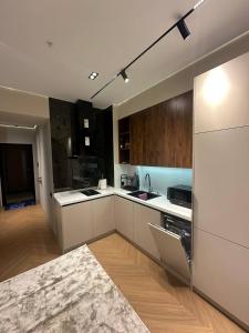 eine große Küche mit weißen Arbeitsflächen und Holzschränken in der Unterkunft TASHKENT CITY PREMIUM NRG U tower 8 floor, 106 in Taschkent