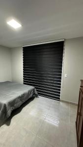 a bedroom with a large window with black blinds at Apartamento completo em Petrópolis in Petrópolis