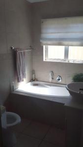 a bathroom with a tub and a sink and a window at StayNow Parklands in Cape Town
