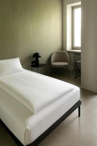 a bedroom with a white bed and a chair at Hotel Mons am Goetheplatz in Munich