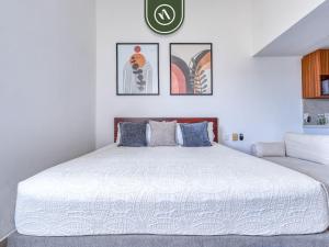 a bedroom with a white bed with four pictures on the wall at Cozy Beachfront Studio - Beach Club - Pools in Nuevo Nayarit +19 photos