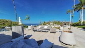 a patio with tables and chairs and the ocean at Amazing Condo - Beach Access - Spa - Pool in Higuera Blanca