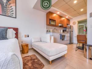 a living room with a white couch and a kitchen at Cozy Beachfront Studio - Beach Club - Pools in Nuevo Nayarit