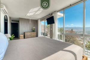 a bedroom with a large bed and large windows at 3 BR Condo - Panoramic Views - 5 Min to Downtown in Oaxaca City