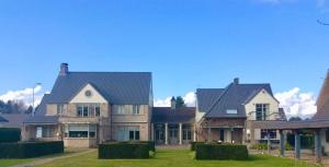 a large house with a roof on a green yard at De Loft in Melsele