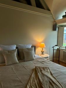 a bedroom with a large bed with pillows and a lamp at De Loft in Melsele