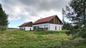 een wit huis met een rood dak in een veld bij Warmińska Polana - Nowy, całoroczny dom na 2 ha łące dla 8 osób - Gietrzwałd in Gietrzwałd