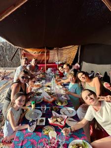 a group of people sitting around a table eating food at Sidi kawiki azro plage in Essaouira
