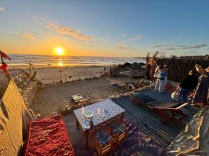 a group of people standing on a beach at sunset at Sidi kawiki azro plage in Essaouira