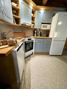 una cucina con mobili bianchi e un frigorifero bianco di Tunnelmallinen hirsimökki - Levin Liitäjä a Kittilä Altre 17 foto
