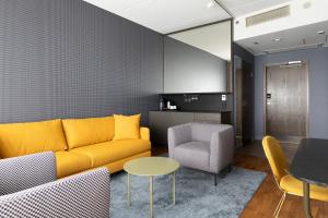 a living room with a yellow couch and a table at Break Sokos Hotel Flamingo in Vantaa